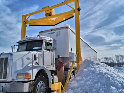 a semi truck driving under a scraper system in winter